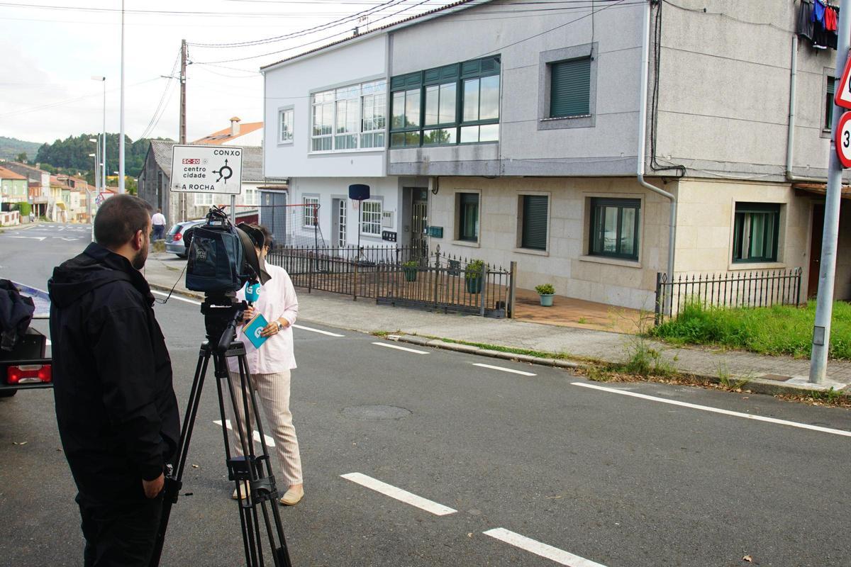 Una reportera informa delante de la casa de la víctima en la calle de Poza Real de Arriba, en Conxo