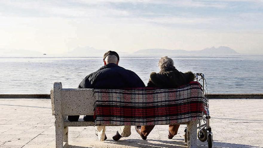 Una pareja de personas mayores contempla el mar en  un banco del paseo de Samil. // Alba Villar