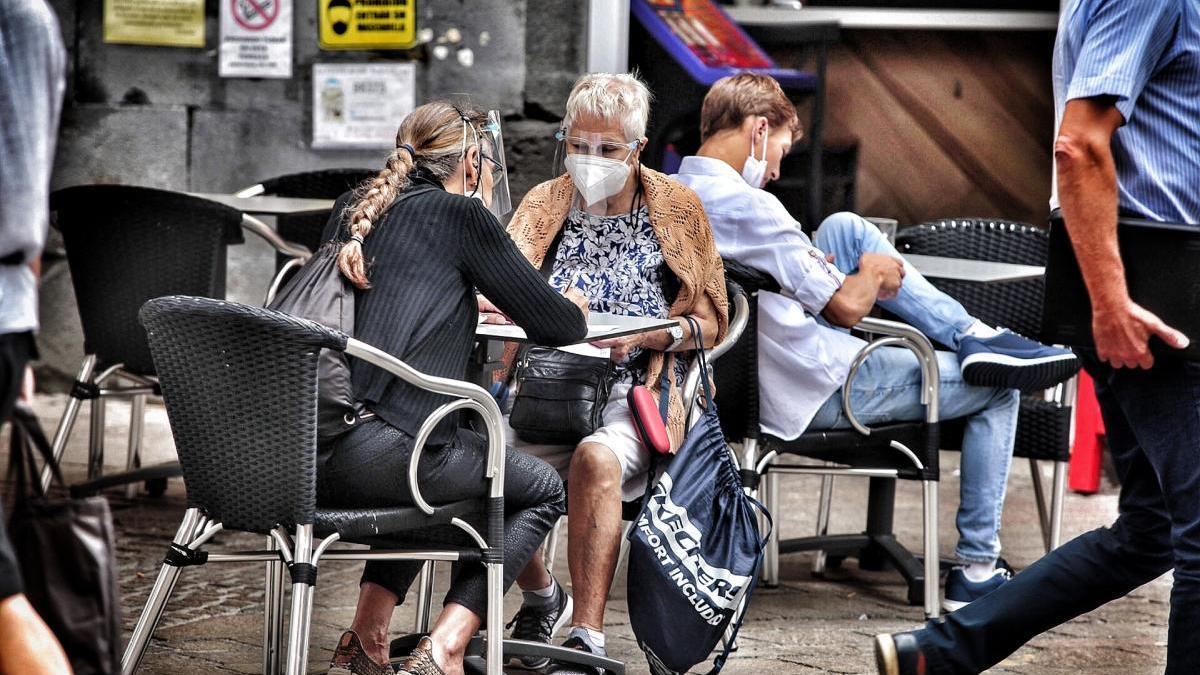 Dos mujeres hablan sentadas en la terraza de una cafetería