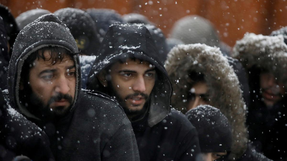 Un grupo de migrantes esperan bajo la nieve en un centro de transporte y logística en la región bielorrusa de Grodno, junto a la frontera con Polonia, este martes.