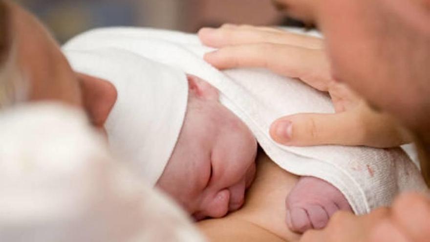 Un recién nacido arropado por su madre y su padre.