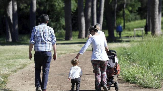 Una parella passeja amb 
el fill per un parc. | IRIA D. POMBO / EFE