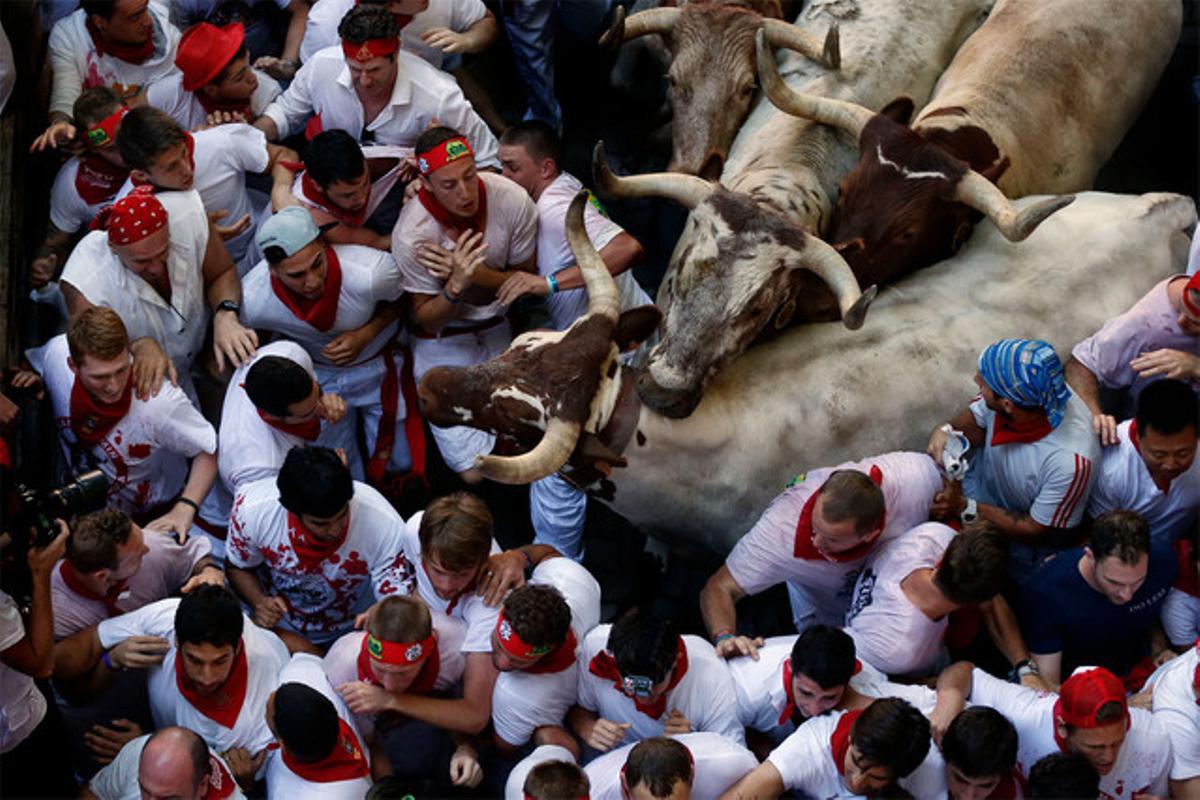 Grups de joves rodegen dos toros. (AP / DANIEL OCHOA DE OLZA)