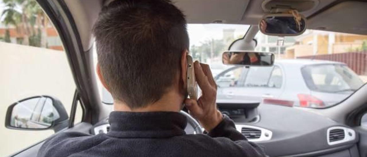 Una persona conduciendo un automóvil, sin utilizar el sistema de «manos libres» para hablar por el teléfono móvil.