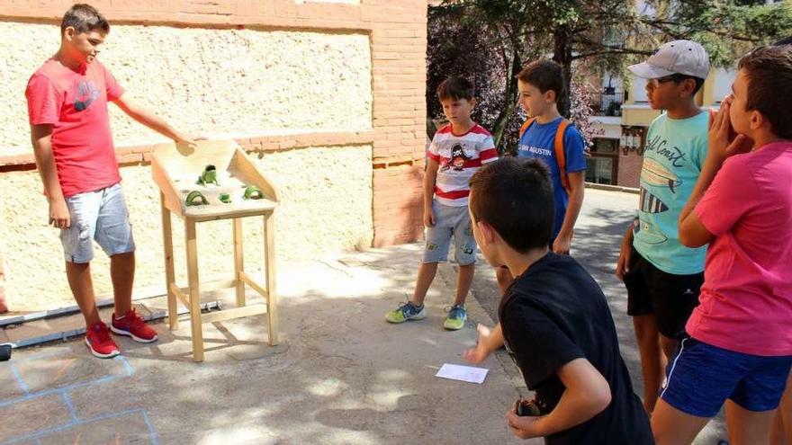 Uno de los jóvenes tira el petaco al tablero de la rana, en el exterior del Punto Joven.