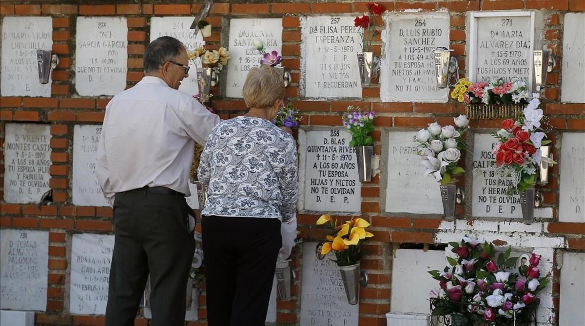 Dos personas cuidan de un nicho en un cementerio de Madrid.