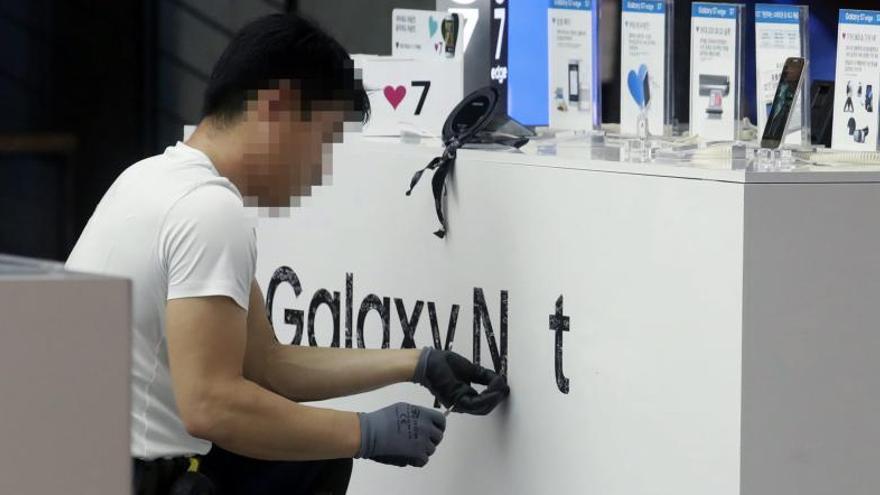 Un operari retira la publicitat del Note 7 en una botiga de Seül.