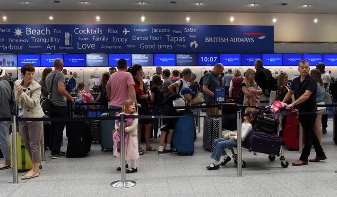 People queue with their luggage for the British ...