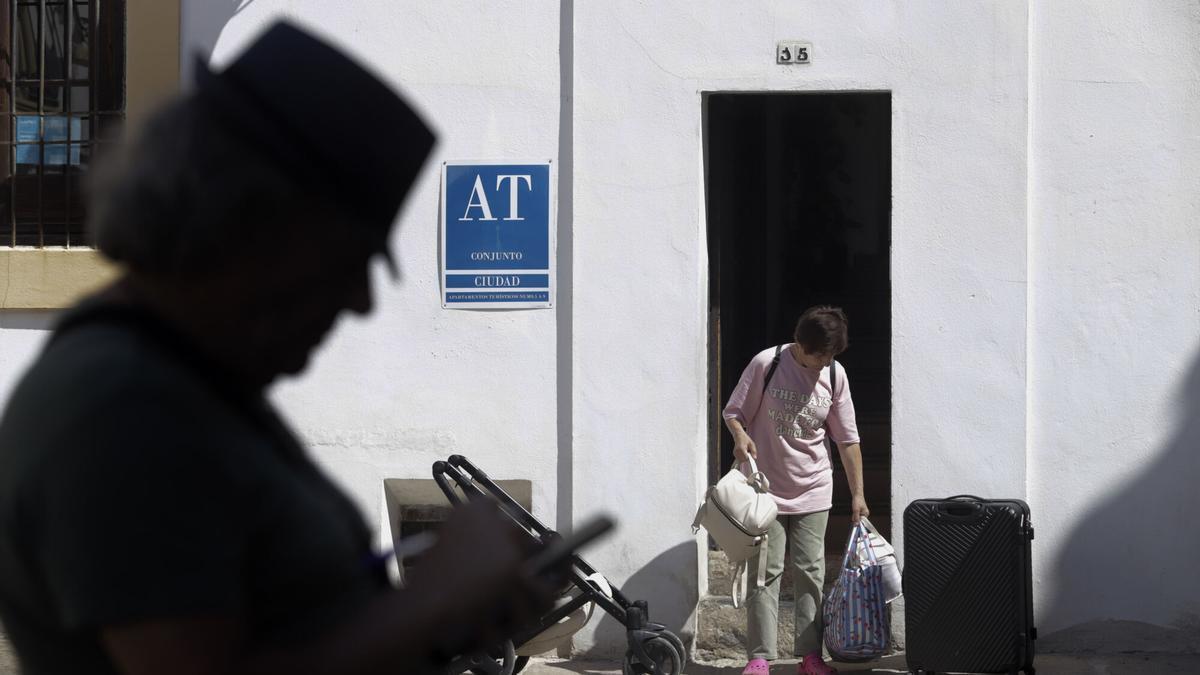 Imagen de archivo de un joven saliendo con maletas de un bloque de apartamentos turísticos de la ciudad.