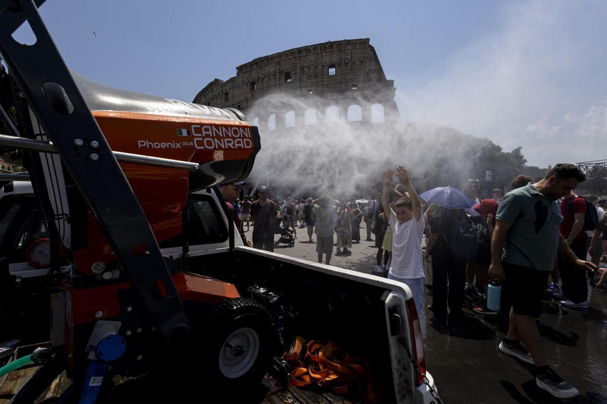 Un camión lanza agua para refrescar a los turistas que acuden a visitar el Coliseo de Roma.