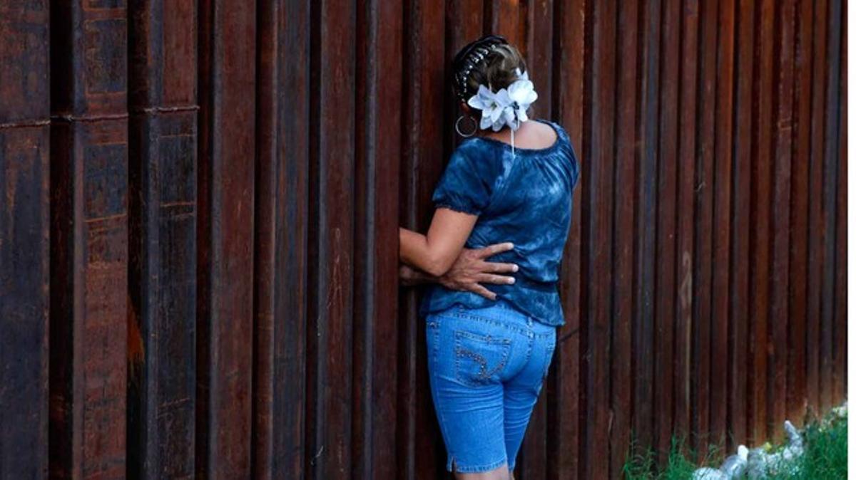 Una mujer habla con su marido a través del muro que separa Arizona de México.