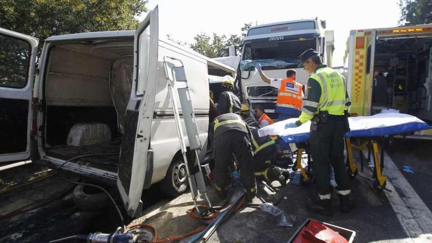 Sanitarios, bomberos y guardias civiles ante la furgoneta y el tráiler del siniestro en la N-550