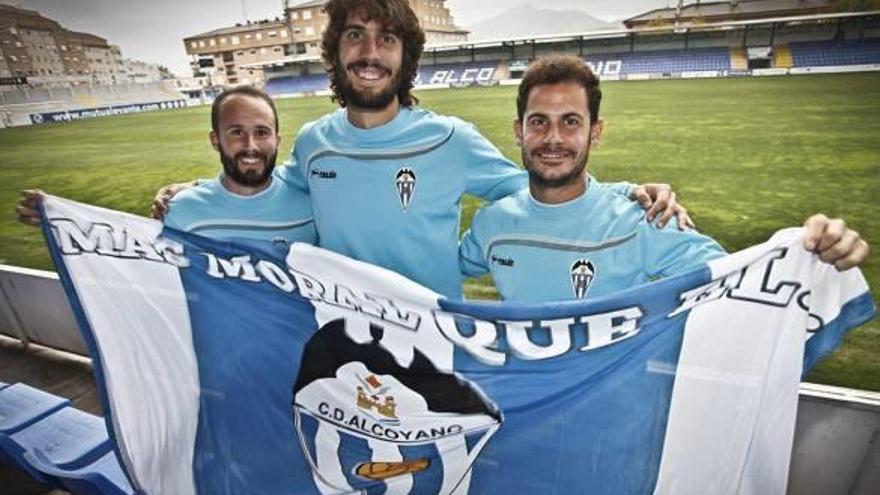 Álvaro García, Mariano Sanz y Gato, ayer, sostienen una bandera del Alcoyano con El Collao de fondo.