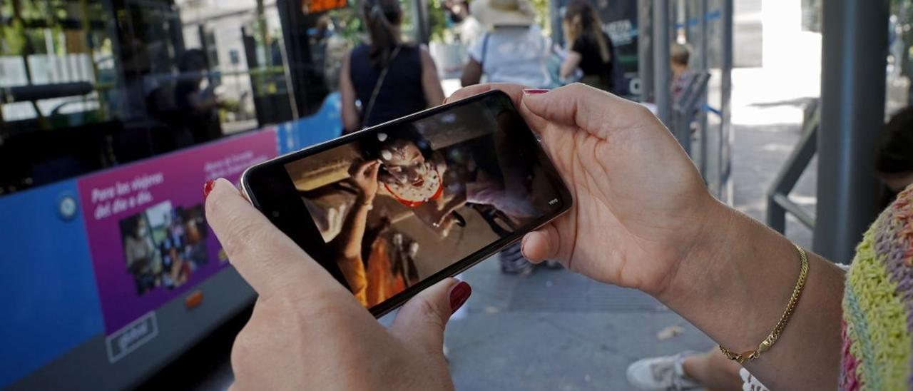 Una joven espera el autobús y se entretiene con un vídeo musical sin auriculares, la semana pasada en Madrid.