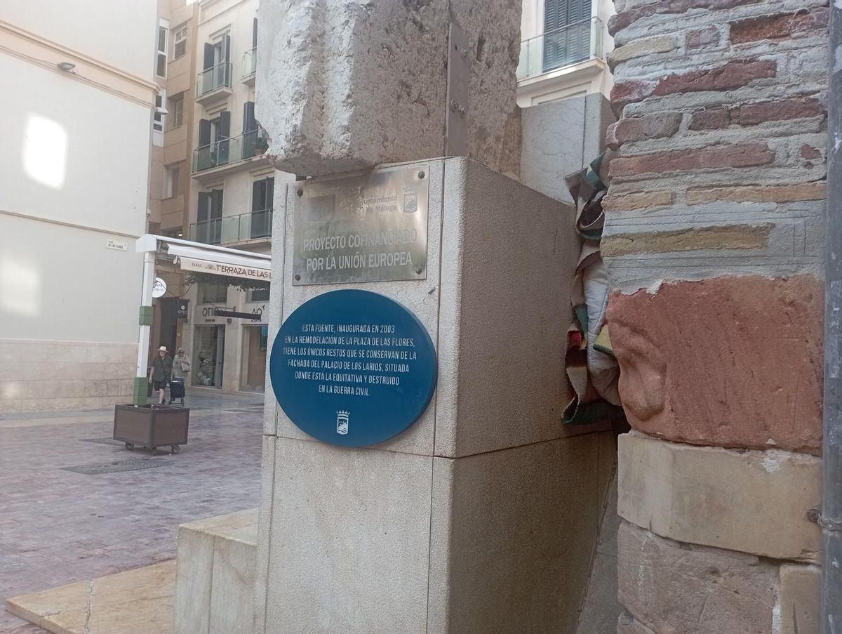 La placa conmemorativa, en el lateral de la fuente y encima, uno de los mármoles de la casa palacio de los Larios.