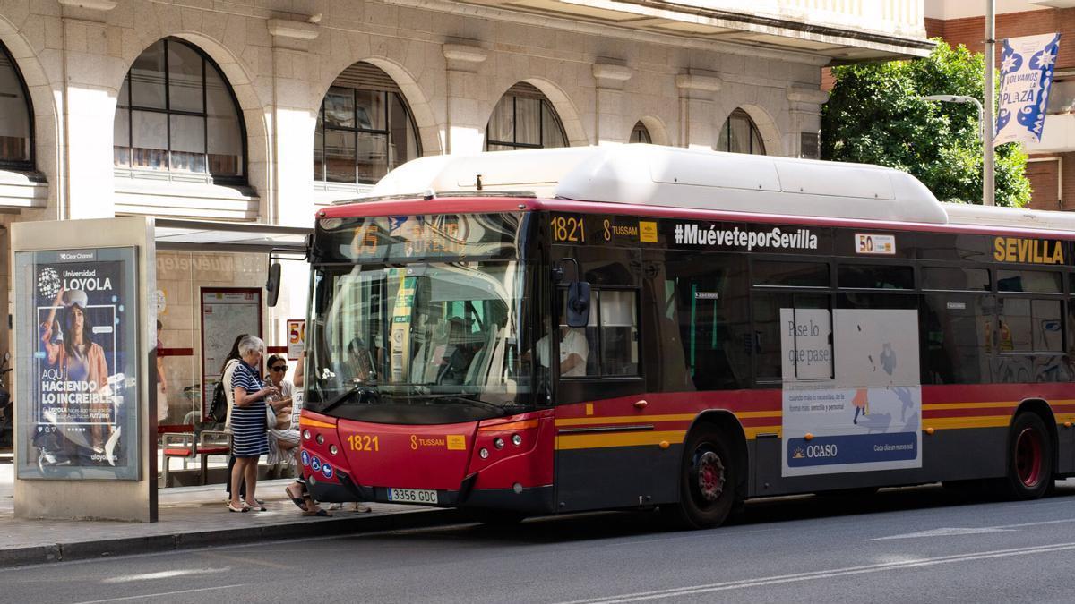 Autobús urbano de TUSSAM (Sevilla) detenido en una parada mientras varios pasajeros suben a bordo