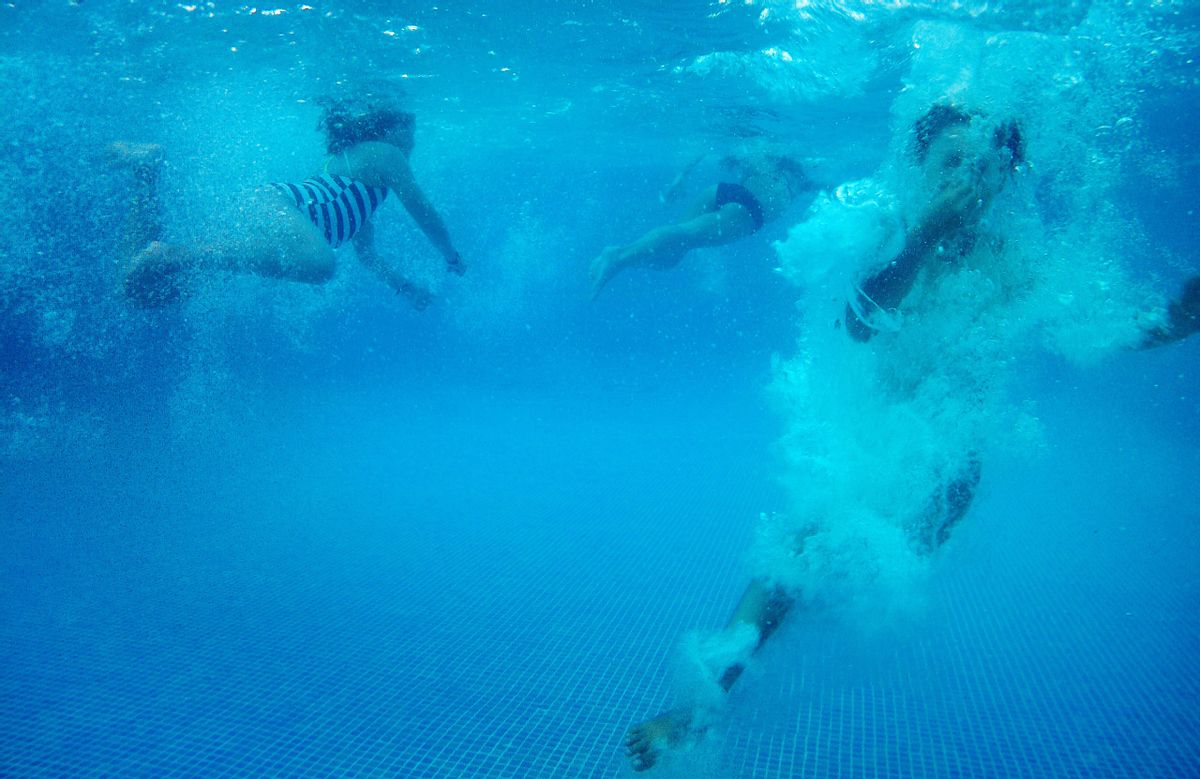 Unos niños nadan en una piscina.