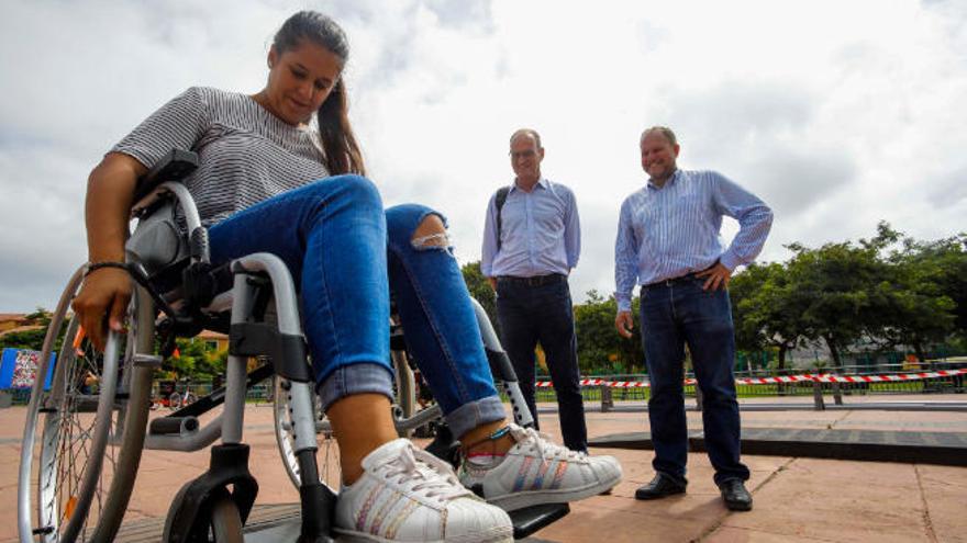 En primer plano, una joven en silla de ruedas. Detrás, Ramírez y Millares.