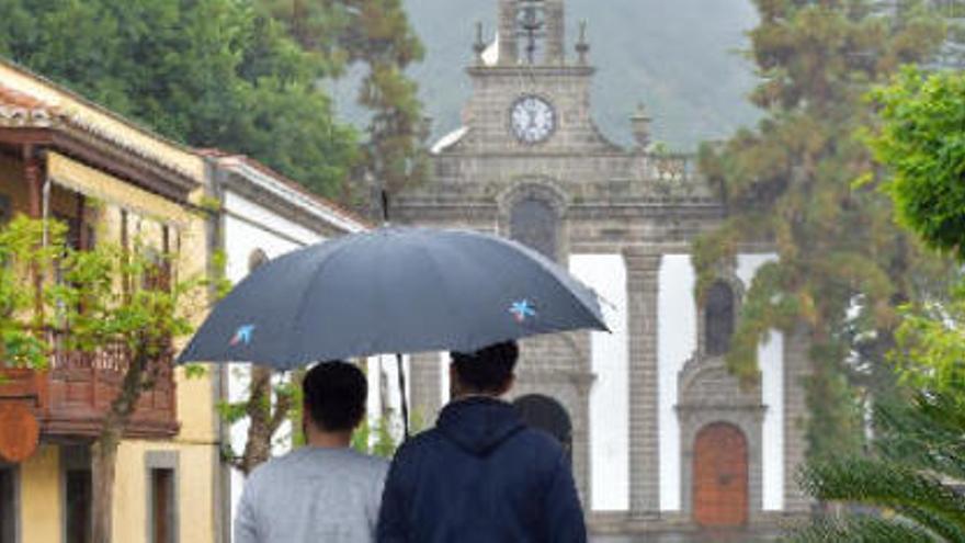 Dos personas pasean por la Calle Real de la Plaza de Teror protegiéndose de la lluvia con un paraguas, en una imagen de archivo.