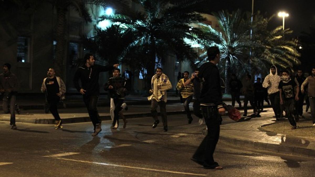 Varios de los manifestantes acampados en la plaza de la Perla, en Manama, huyen de la carga policial, la noche del miércoles.