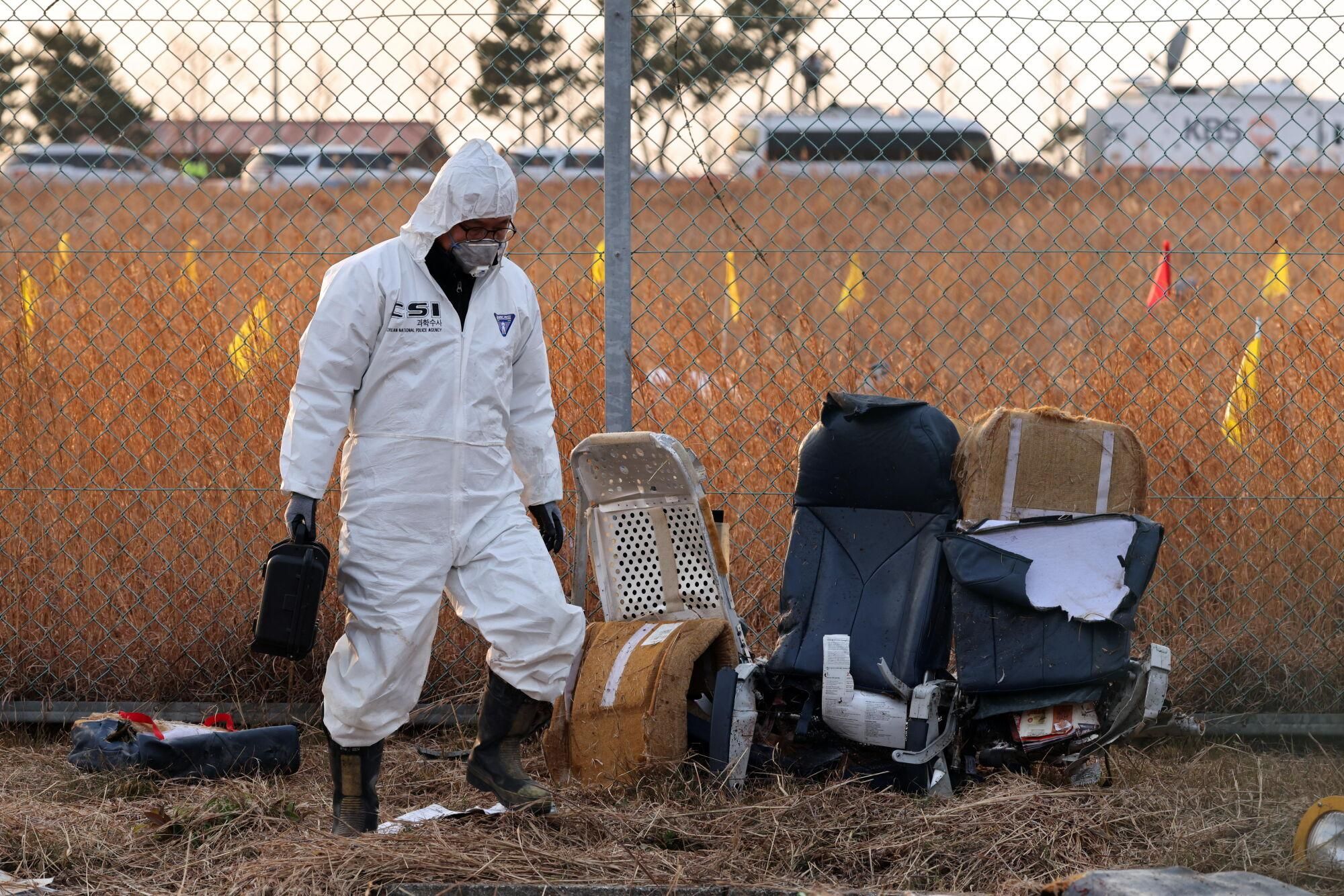 Muan (South Korea), 29/12/2024.- A member of Korea Crime Scene Investigation (KCSI) inspects the wreckage of the Jeju Air aircraft at Muan International Airport in Muan, 288 kilometers southwest of Seoul, South Korea, 29 December 2024. According to the National Fire Agency, a passenger jet carrying 181 people erupted in flames after going off the runway at an airport in South Korea's southwestern county of Muan on 29 December, leaving at least 62 people dead. (Corea del Sur, Seúl) EFE/EPA/HAN MYUNG-GU