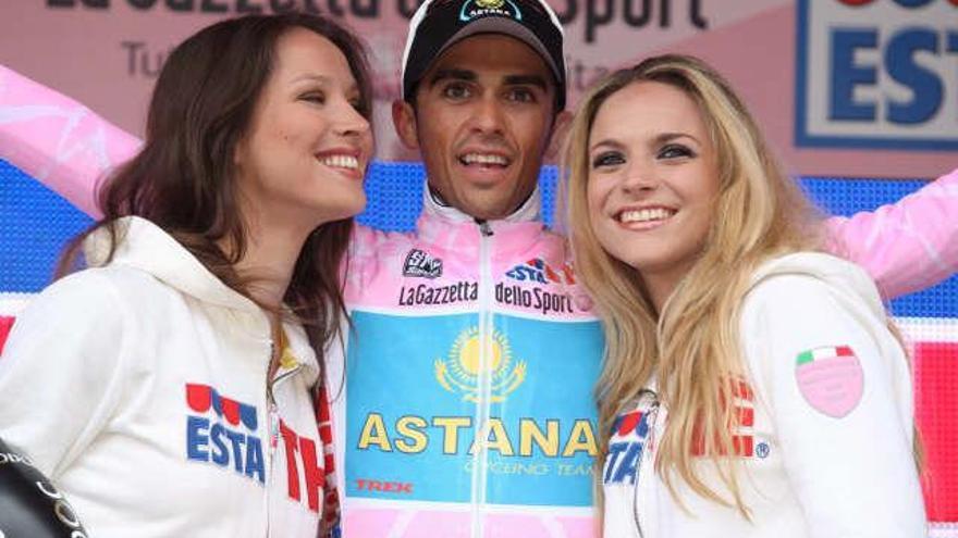 El ciclista español Alberto Contador (c) posa en el podio vestido con la &quot;maglia&quot; rosa y acompañado por dos azafatas tras la decimoquinta etapa del Giro de Italia en Passo Fedaia, cerca de la localidad italiana de Belluno.