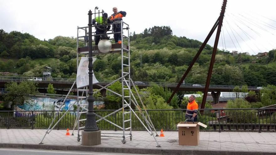 Operarios sustituyendo las luminarias del puente de Sama en mayo del pasado año.