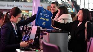 Una trabajadora del aeropuerto de Pristina entrega a una pasajera una bolsa con el mensaje SinVisado, este lunes.