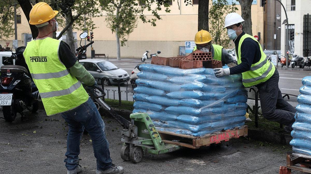 Varios obreros empujan material de construcción necesario para rehabilitar un edificio, en Madrid, el lunes pasado