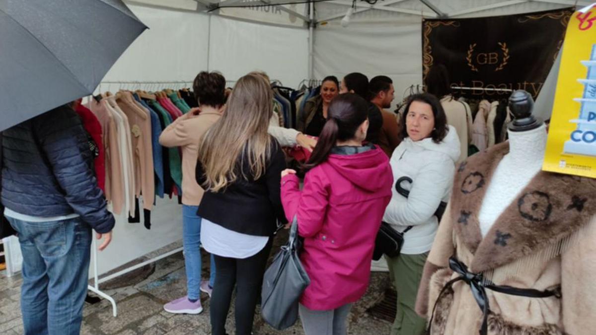 La lluvia animó a los visitantes a meterse en los puestos. | E. P.