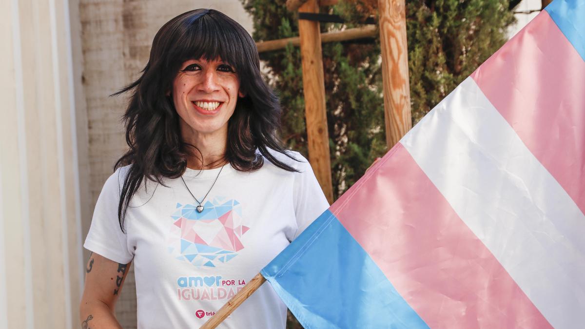 Victoria Mendez Rodríguez posa en la Ciudad Monumental de Cáceres con la bandera trans.