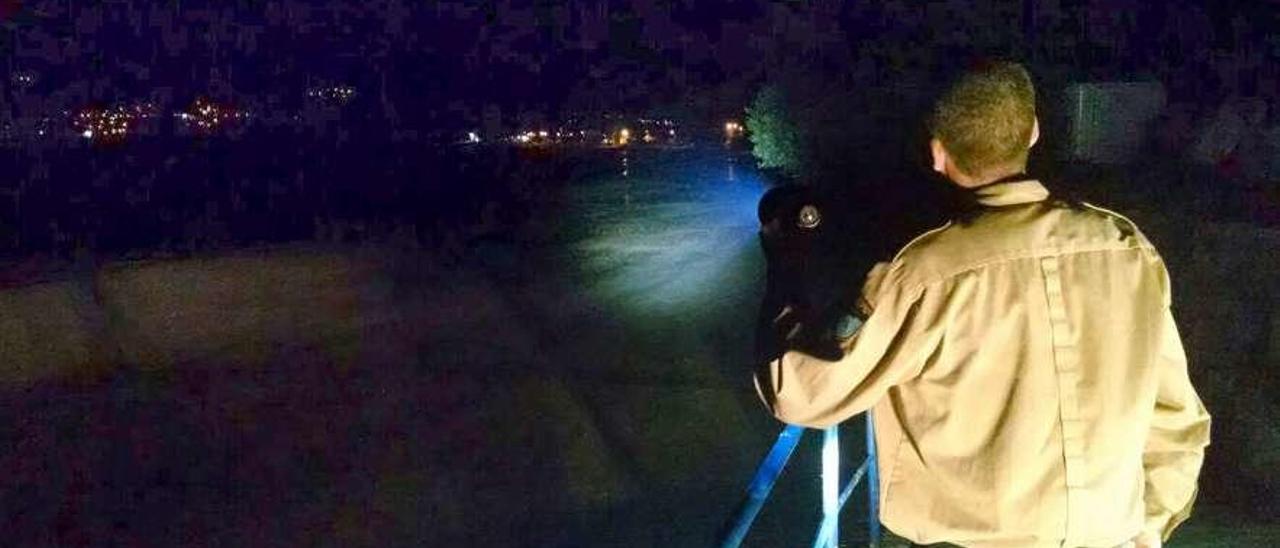 Un guardapesca apunta con su linterna a la playa en Cesantes, Redondela. A.A.