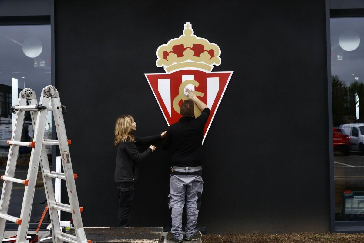 Operarios colocando el escudo en una de las fachadas de la cafetería.