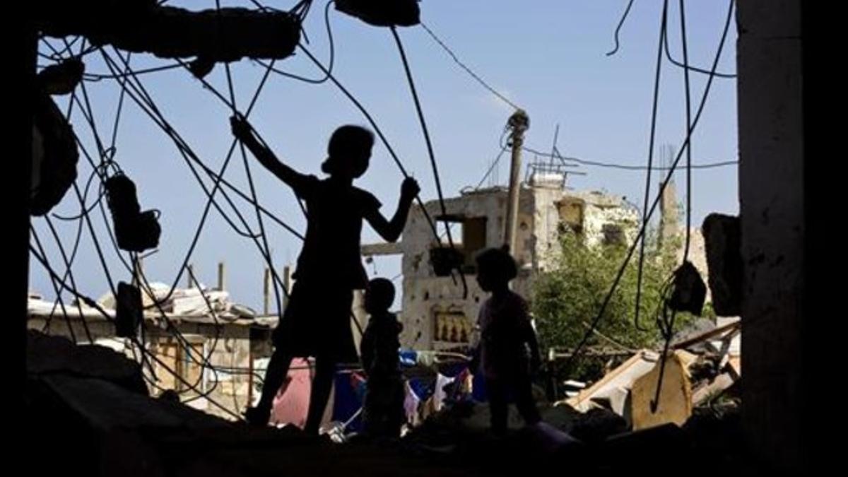 Unos niños palestinos juegan en las ruinas de un edificio destruido.