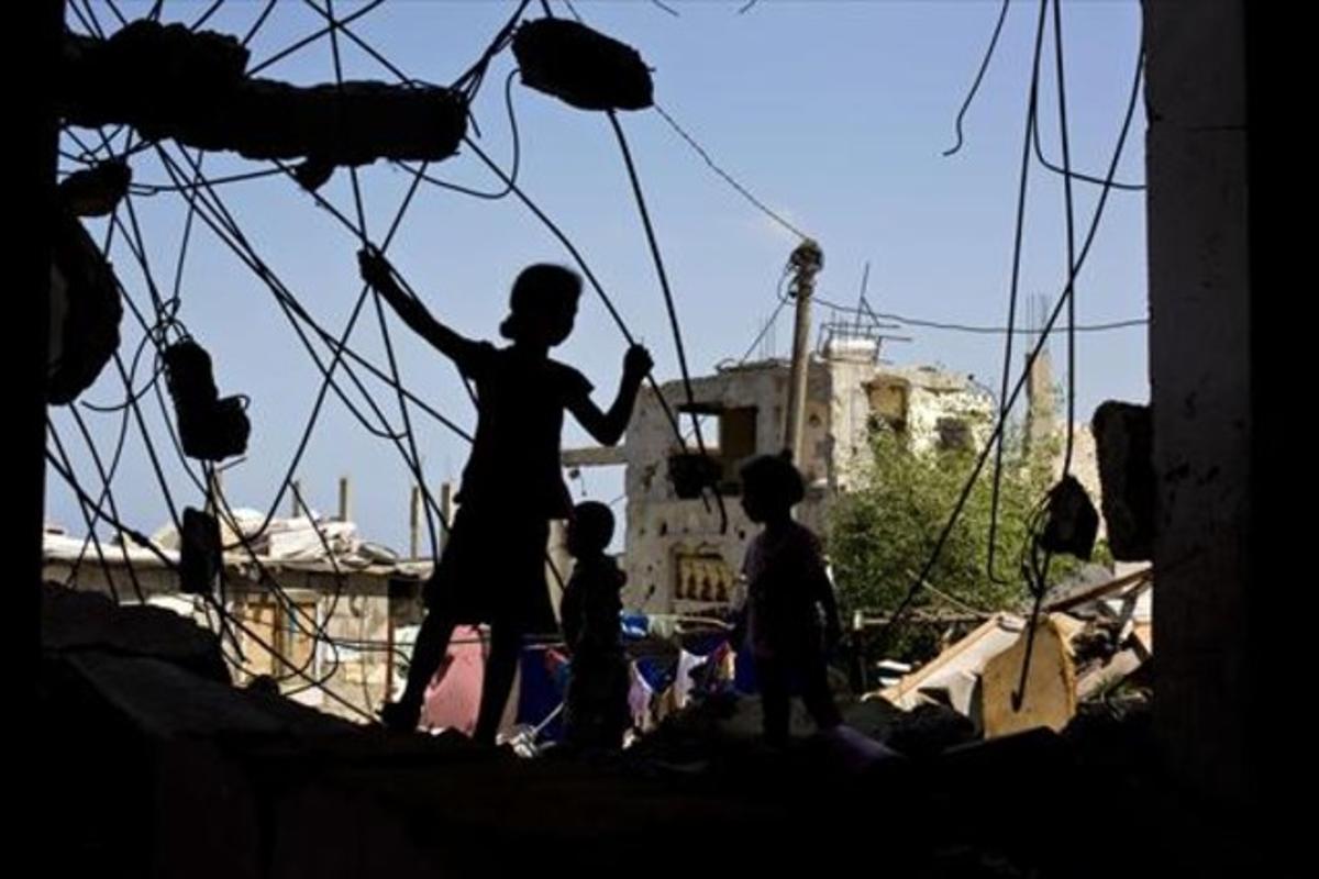 Unos niños palestinos juegan en las ruinas de un edificio destruido.