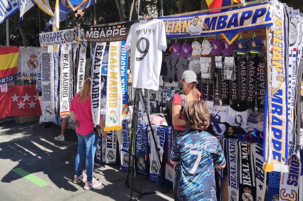 Puesto de banderas y bufandas en los alrededores de un Bernabéu consagrado a Mbappé.