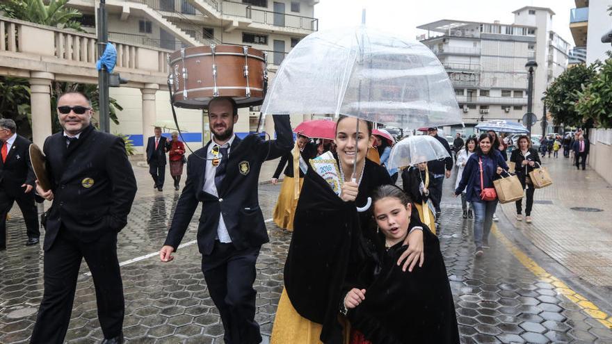 Damas y músicos se cubren de la lluvia, al término de la mascletà