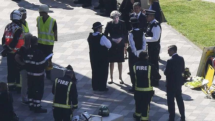 La primera ministra británica, Theresa May, conversa con policías durante su visita a la torre Grenfell.