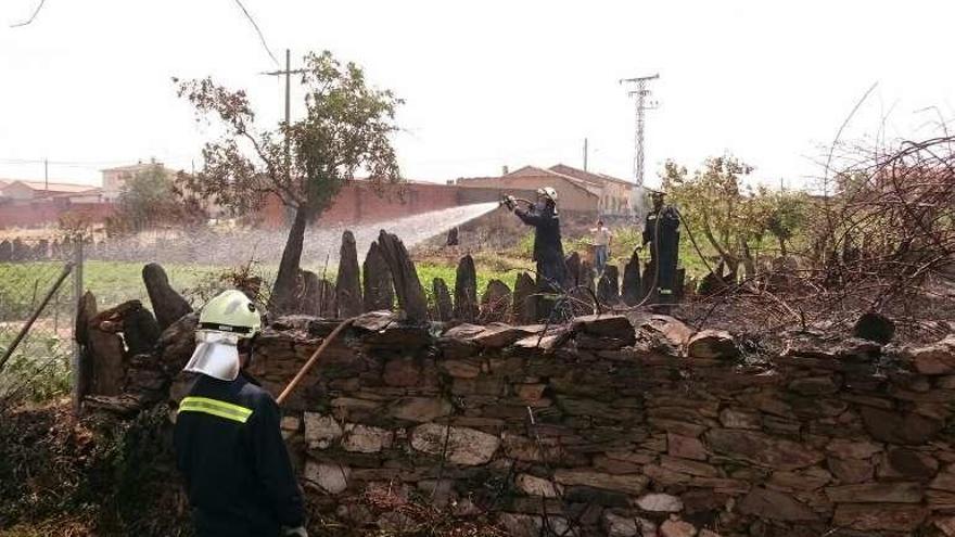 Los bomberos esparcen agua en la zona del fuego.