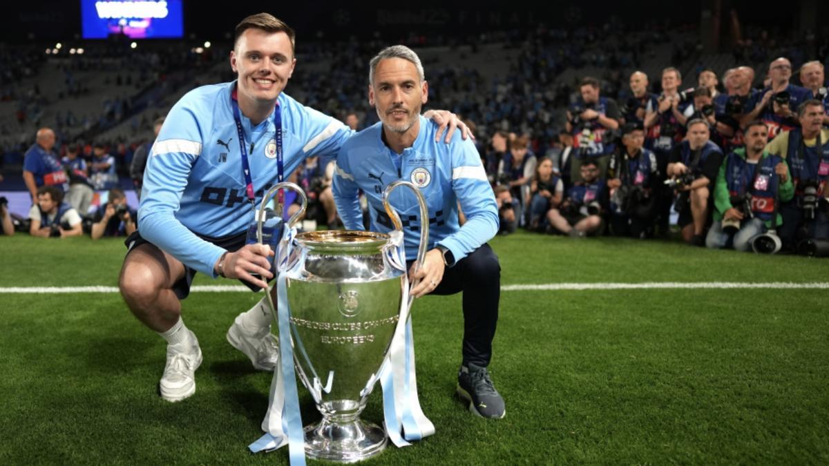 Carlos Vicens posa junto a otro miebro del cuerpo técnico del Manchester City con el trofeo de la Champions League