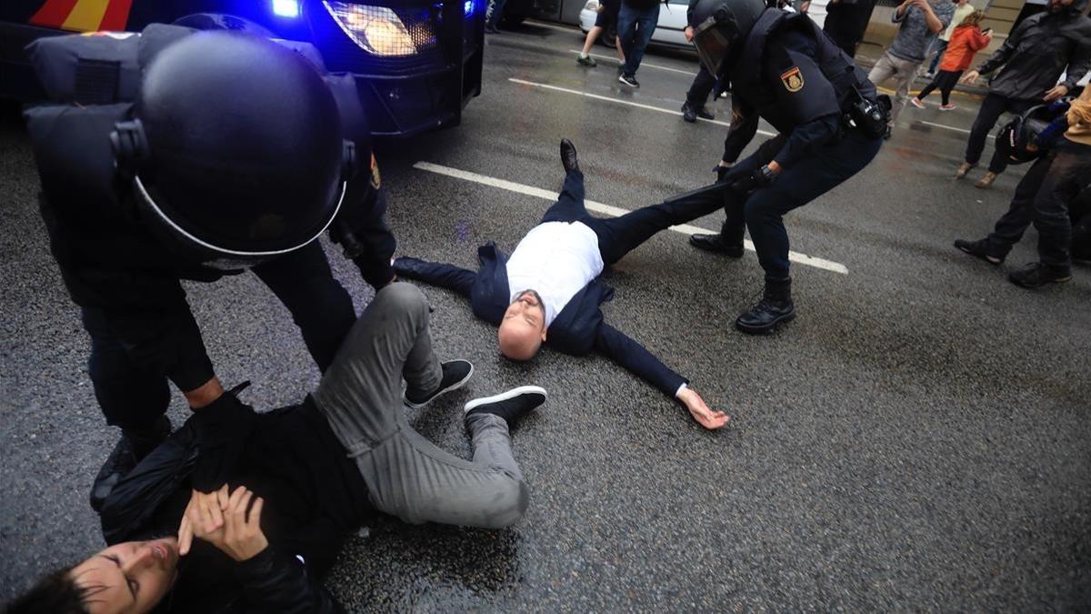 Agentes policiales actúan contra quienes impiden el paso de la Policía Nacional tras la carga en la escuela Ramon Llull, el 1-O.