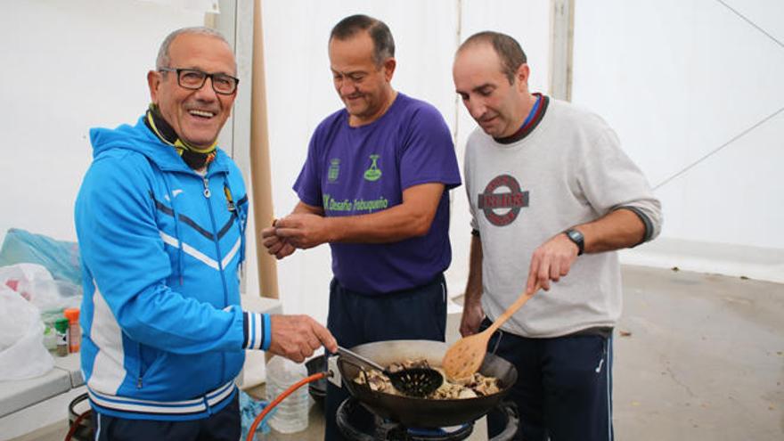 Miembros de una asociación cocinando la porra caliente con setas.