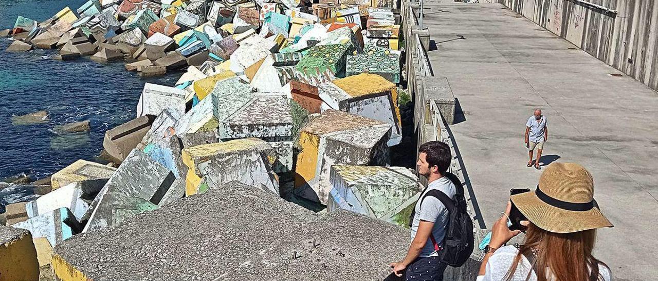 Una pareja de turistas, ayer, fotografiándose junto a los Cubos de la Memoria del puerto de Llanes.