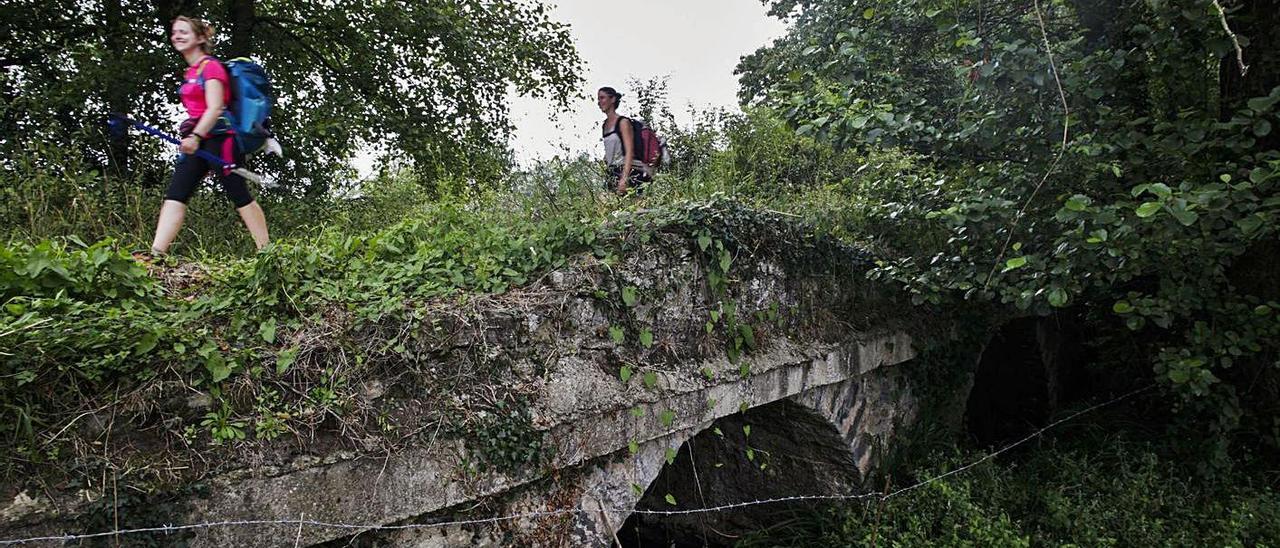 Dos peregrinas cruzan el puente de La Campa, en un tramo castrillonense del Camino de Santiago. | Ricardo Solís