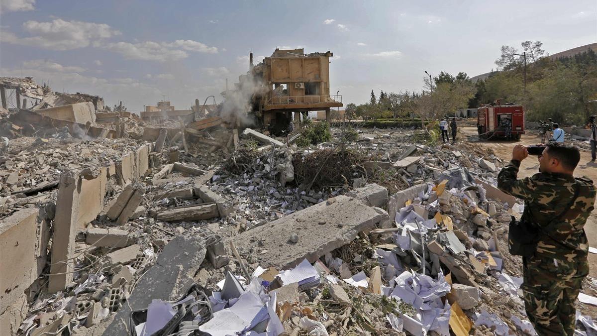 Un soldado sirio toma fotos de los escombros de un edificio bombardeado en la operación liderada por EEUU, que formaba parte del Centro de Estudios e Investigaciones Científicas, en Damasco.