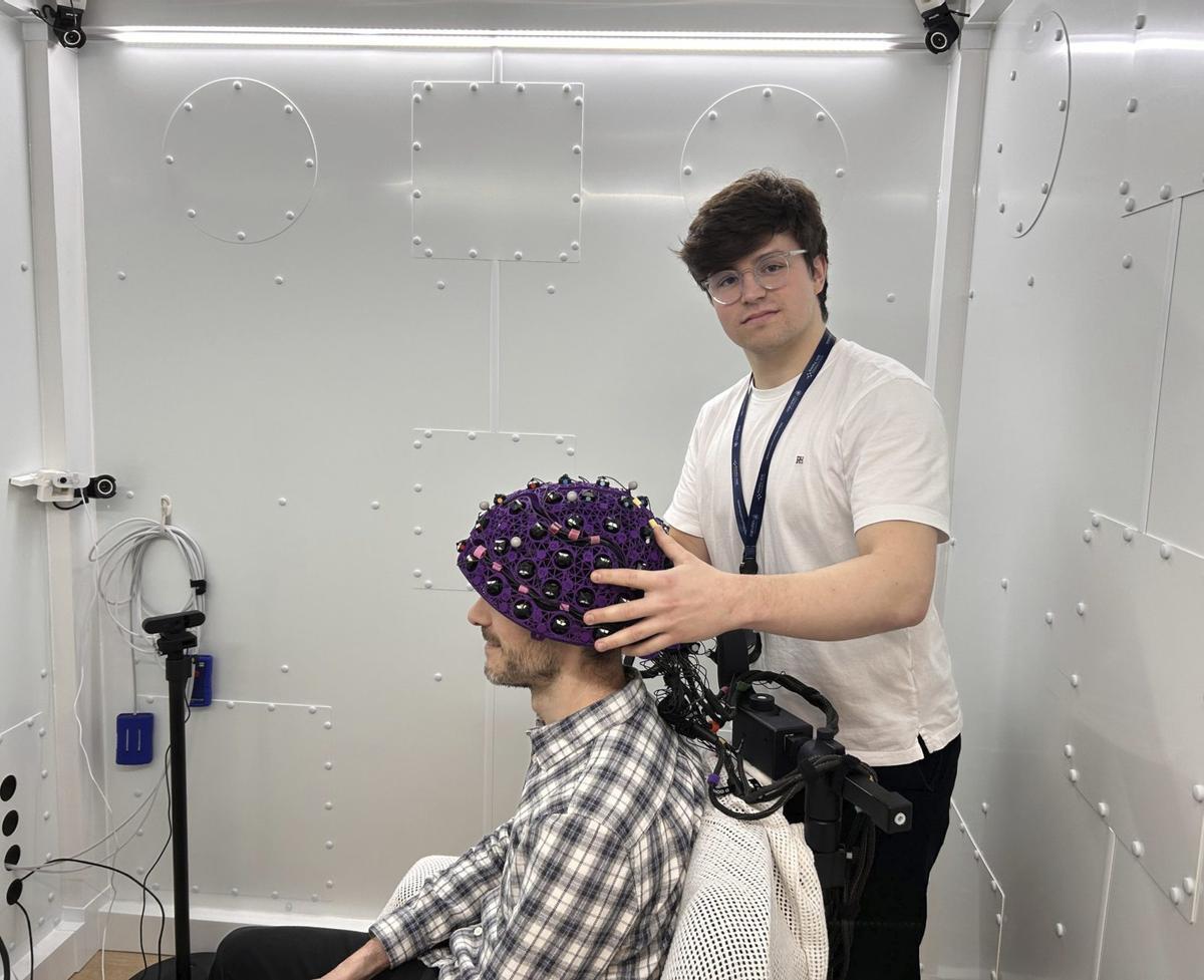 Manuel Rico coloca o escáne OPM-MEG al investigador postdoctoral Rob Seymor en una sala blindada equipada con cámaras del Oxford Centre for Human Brain Activity