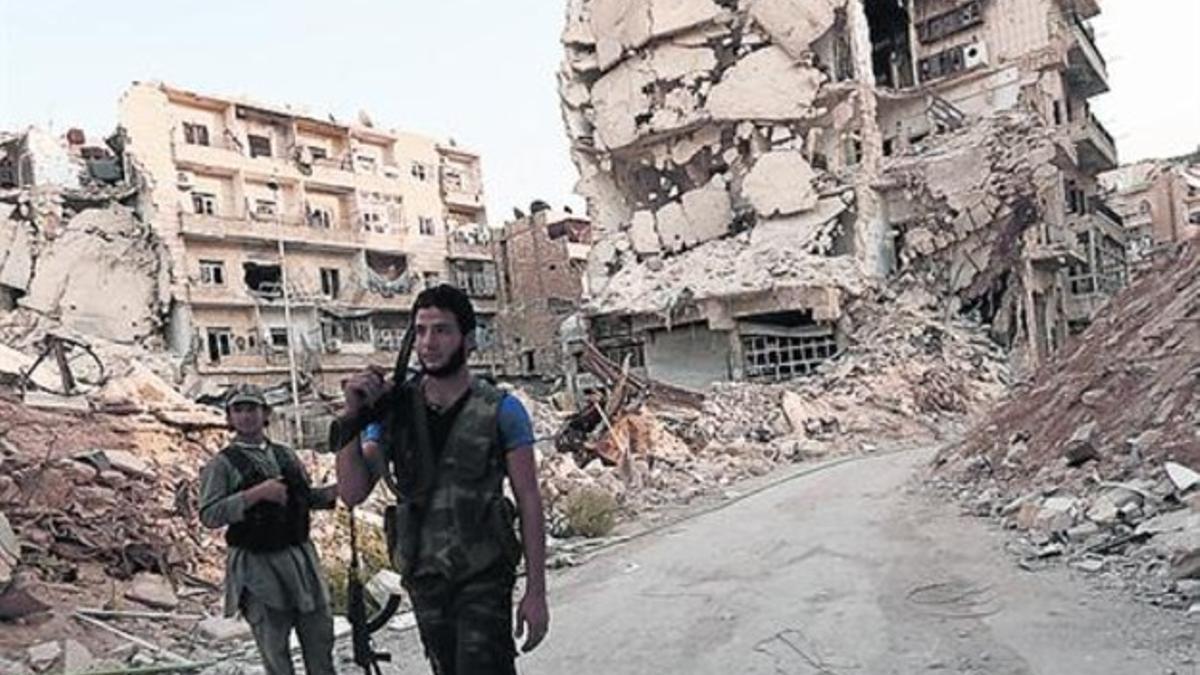Combatientes rebeldes transitan por una calle de Alepo (Siria).