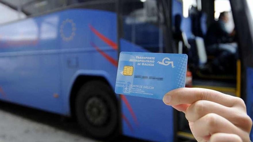 Una usuaria muestra la tarjeta del servicio, con uno de los autobuses de fondo. // Bernabé/Javier Lalín