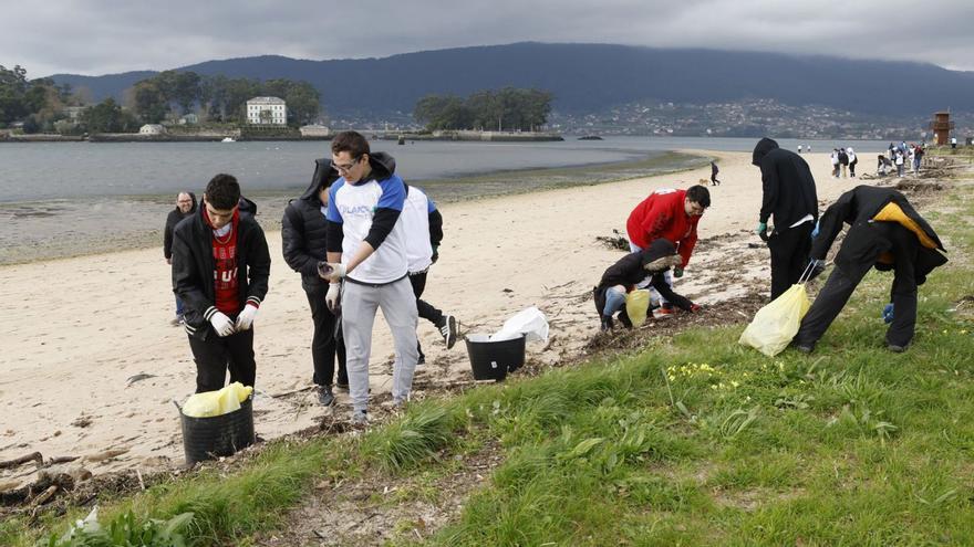 Participantes en la jornada de voluntariado ambiental limpian la playa, ayer por la mañana.   | // RICARDO GROBAS