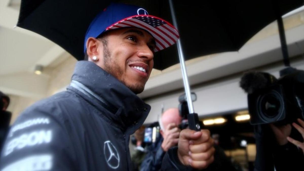 Lewis Hamilton sonríe bajo la lluvia tras suspenderse la sesión de clasificación.